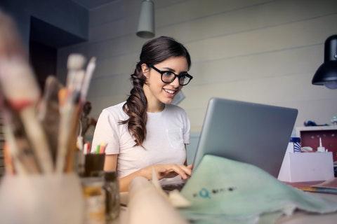 Zjęcie przedstawia kobiete która siedzi przed komputerem